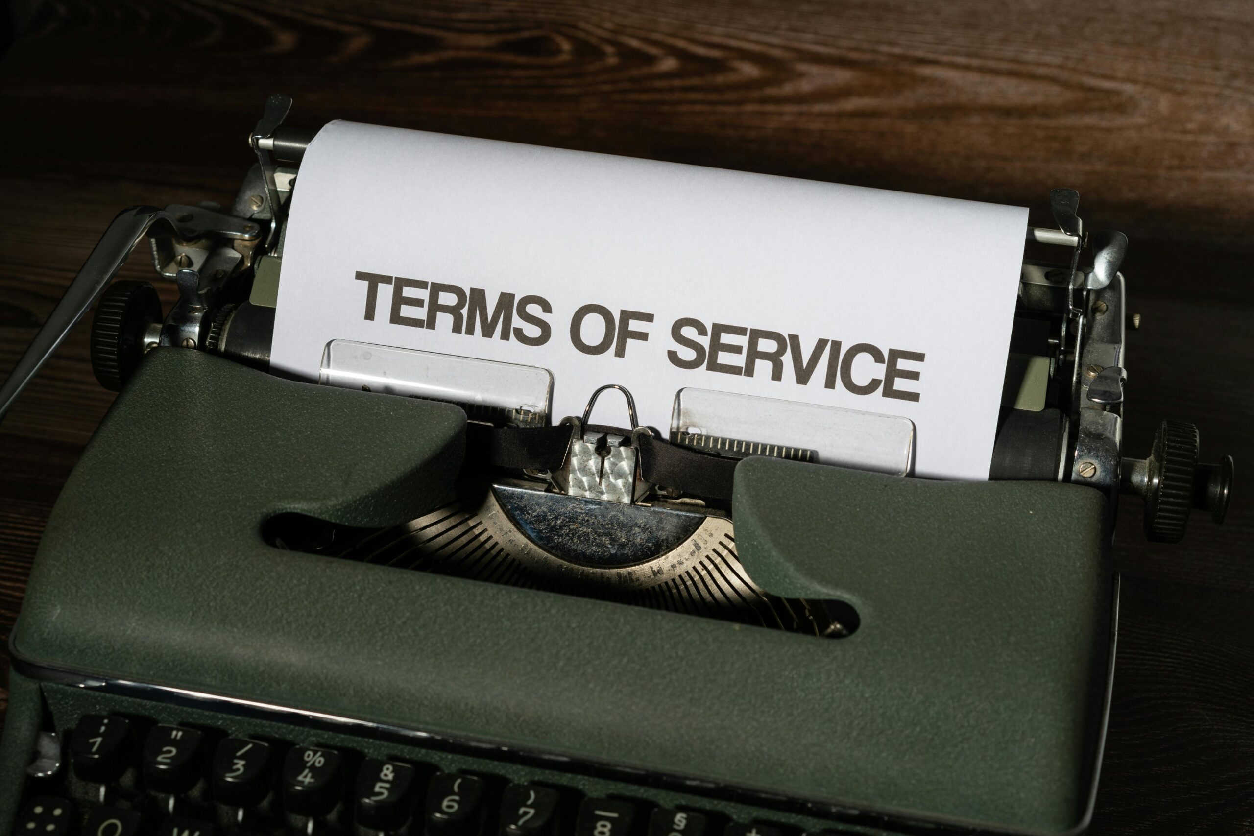 pexels-photo-12153576-12153576 Close-up of a vintage typewriter with 'Terms of Service' paper inside, on a wooden desk.